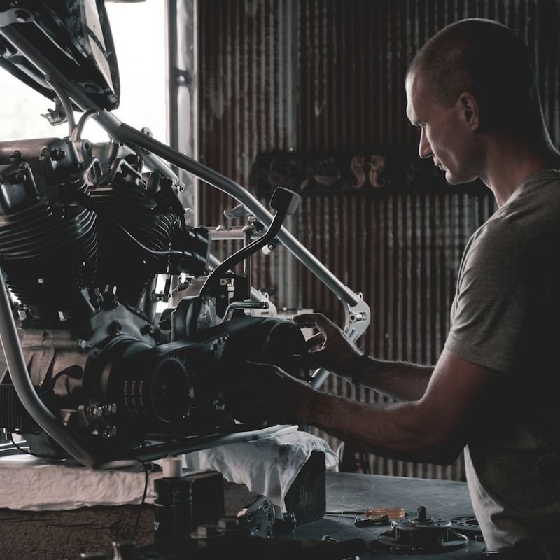 Mechanik naprawiający silnik motocyklowy w warsztacie